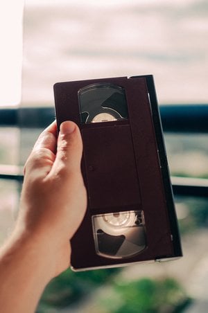 Hand holding video cassette to symbolize the benefits of video interview software