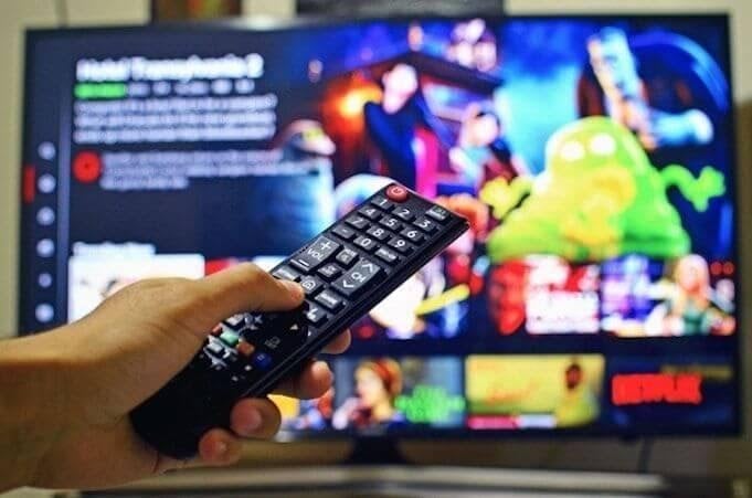 A person holding a remote for a TV subscription