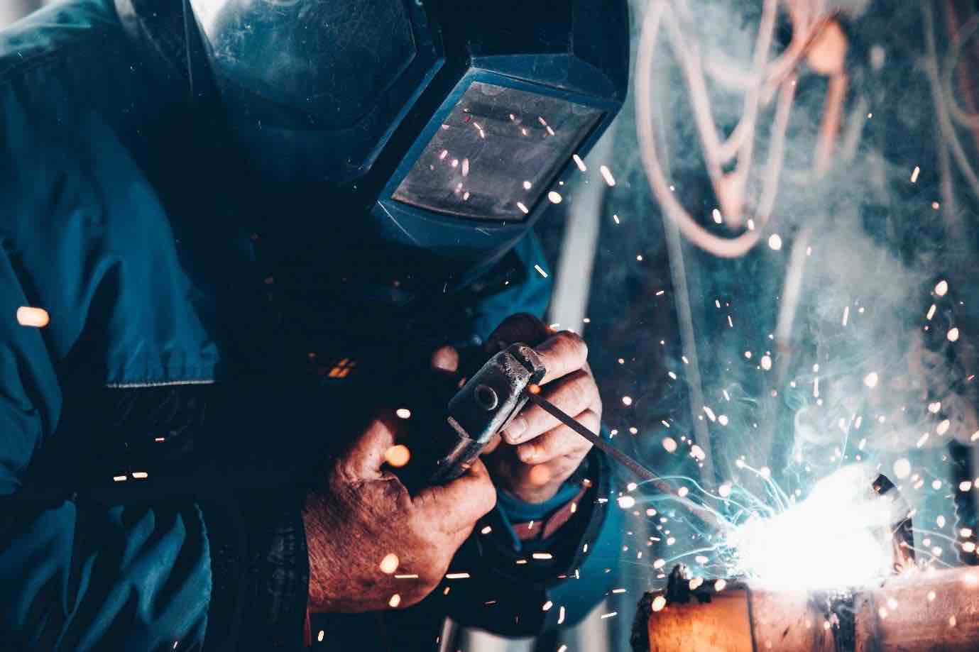 A welder wearing a safety mask while sparks fly
