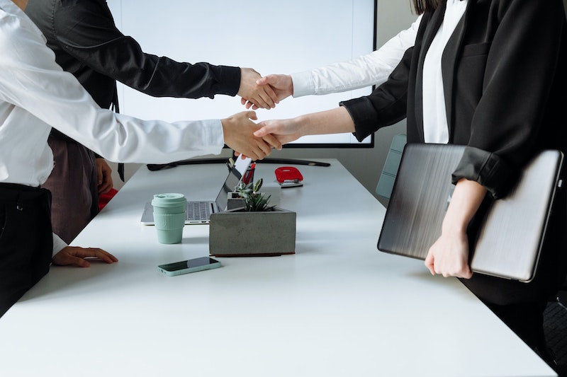 Two company managers shaking hands with two clients