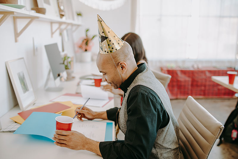 An employee wearing a party hat on his work anniversary. 