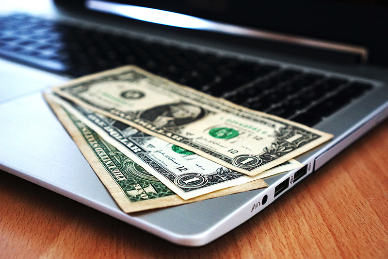 US currency on a laptop keyboard to depict the cost of employee benefits.