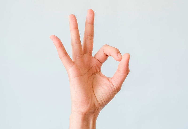 A hand with palm facing the camera performing the ‘OK gesture’ in response to positive feedback.