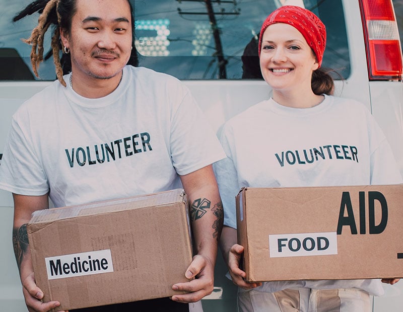 Two volunteers holding boxes of donated medicine and food.