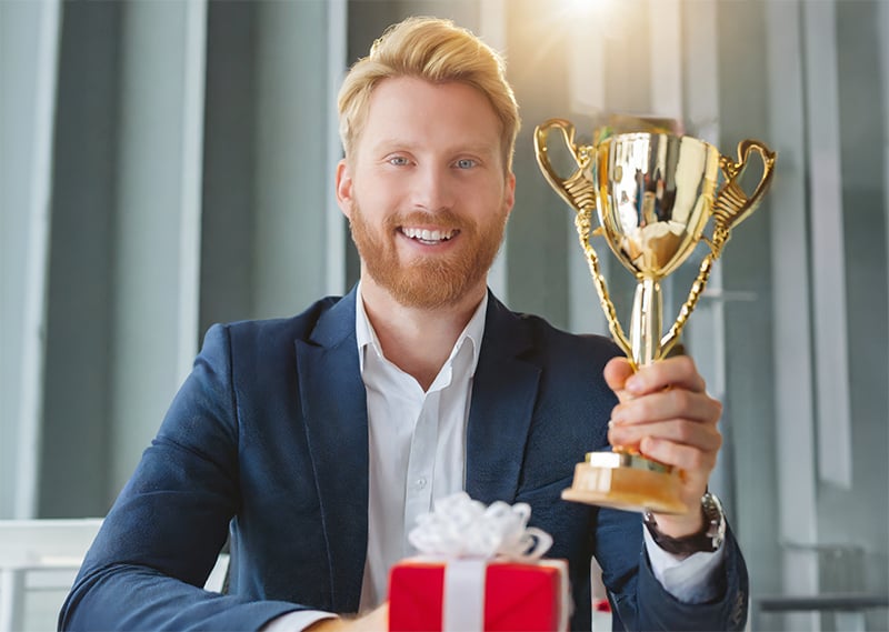 An employee holding a trophy they won as part of the company’s employee rewards program.