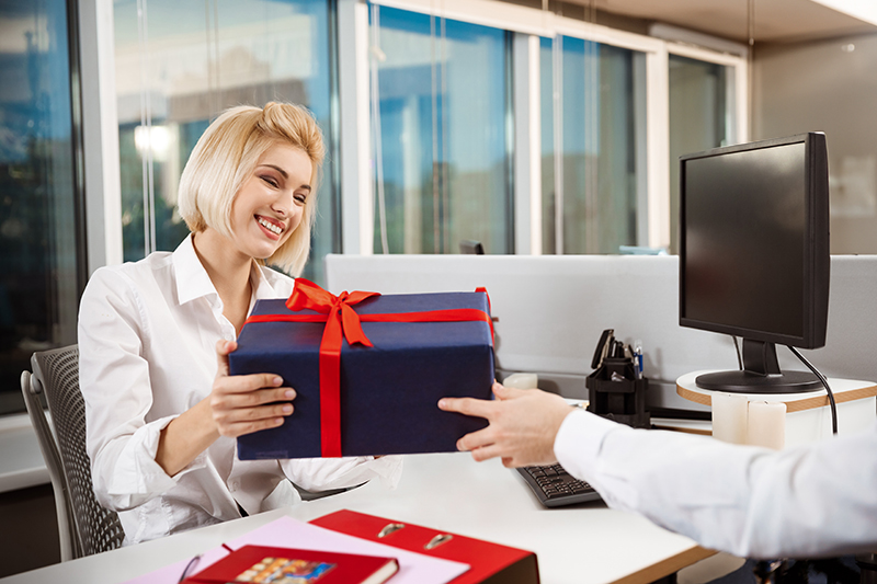 A delighted worker at her desk receiving a gift as an employee reward. 