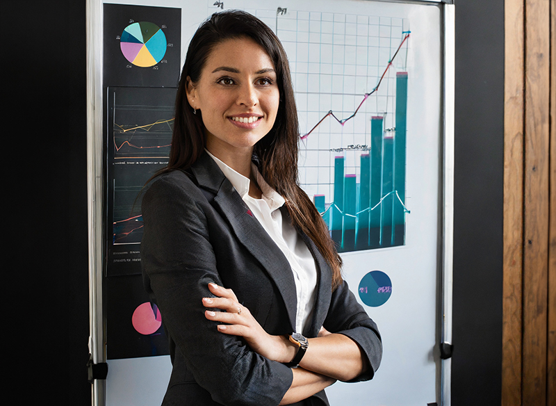 An HR professional standing in front of a board covered in HR analytics charts.