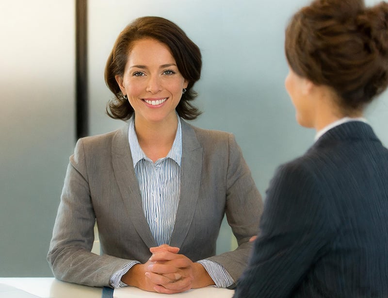 A professionally dressed woman sitting in a job interview for an HR position.